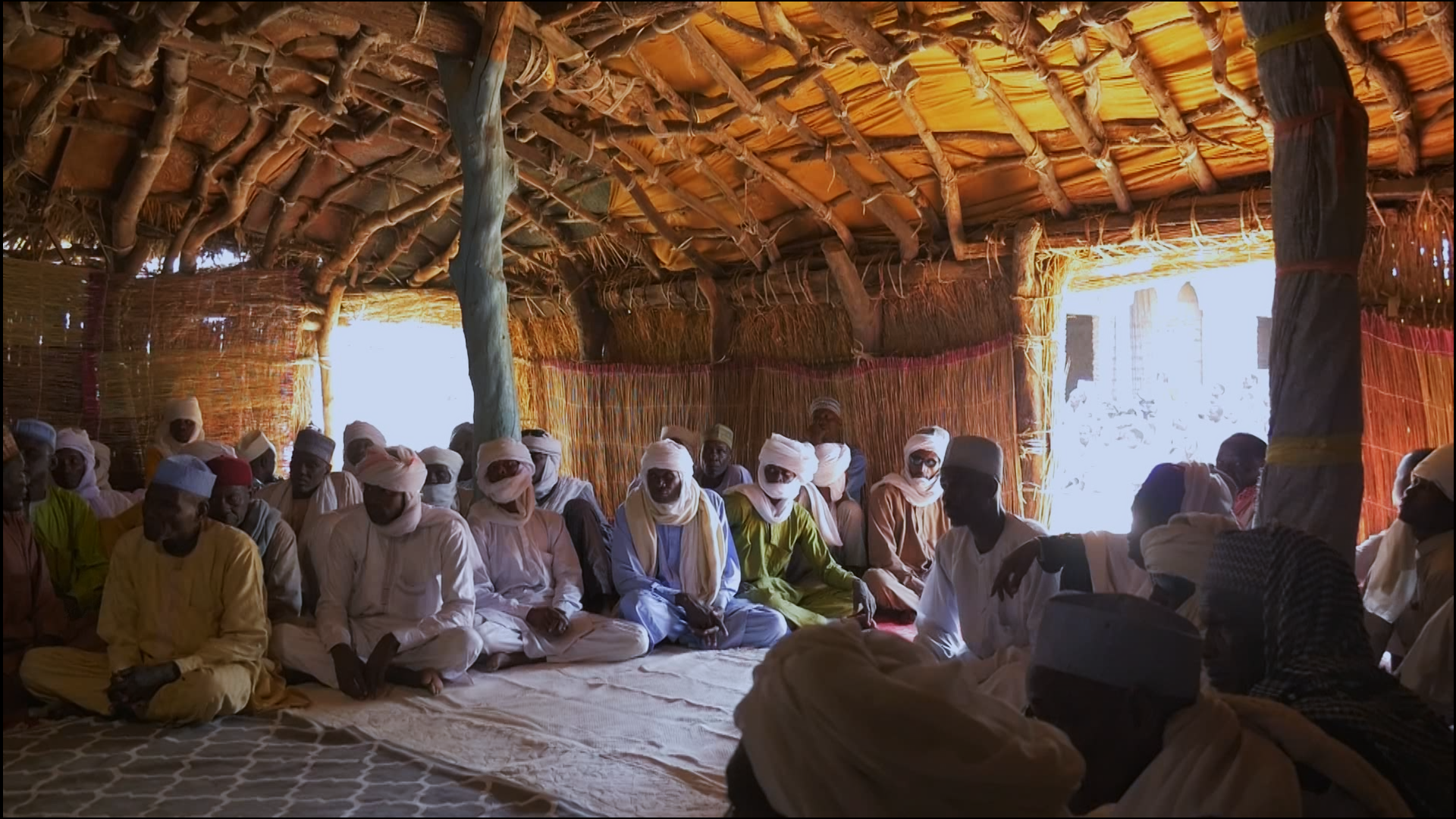 Community members gathered together beneath a shaded shelter