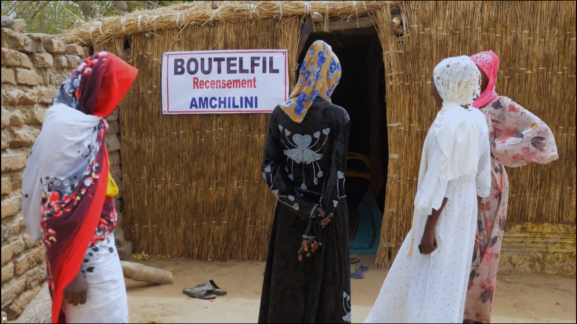 A woman standing beside an Amchilini registration board