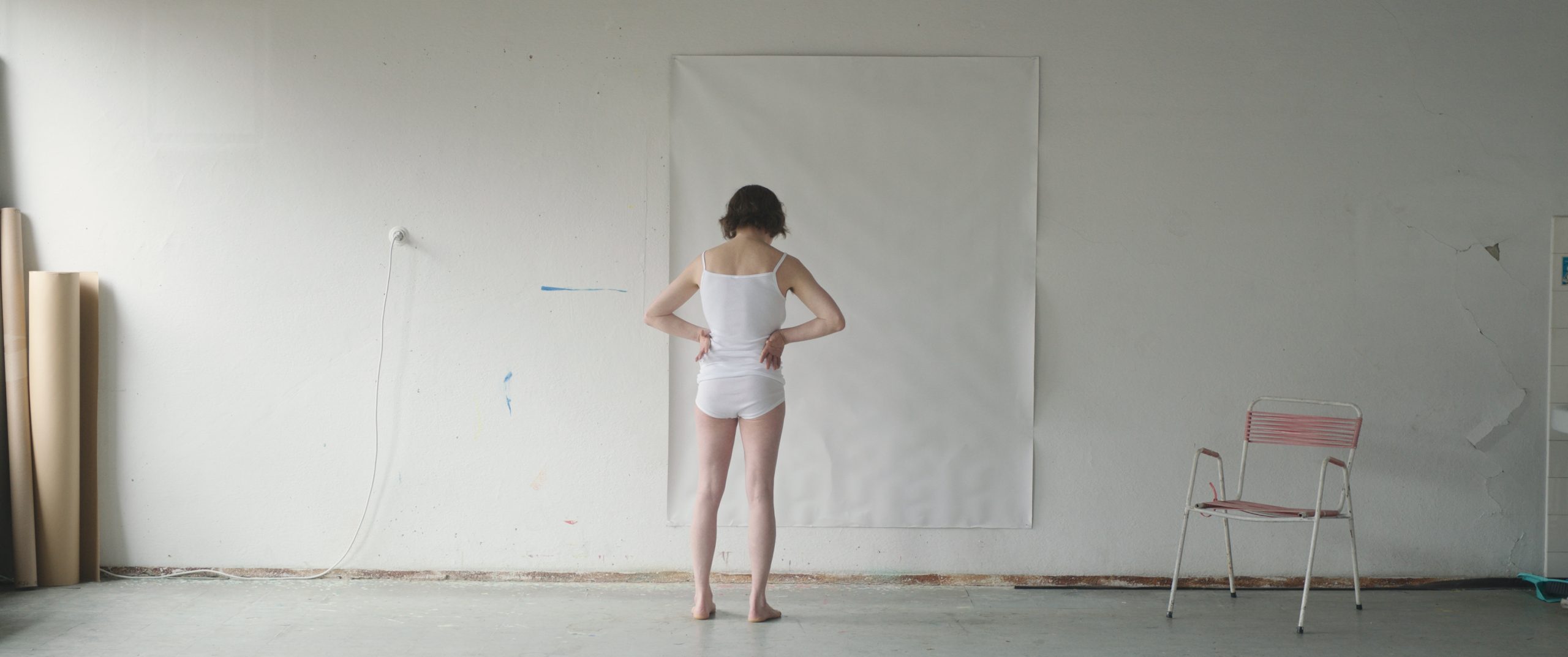 A figure standing against a white studio wall in Sleeping with a Tiger